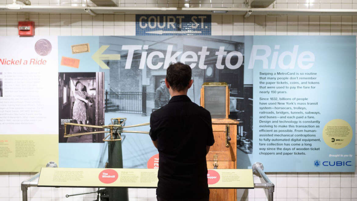 Man standing in front of ticket chopper on view in Ticket to Ride exhibit